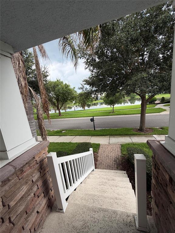 A view from a front porch looking down concrete steps toward a street and pond — 7840 WINTER WREN STREET, WINTER GARDEN, FL