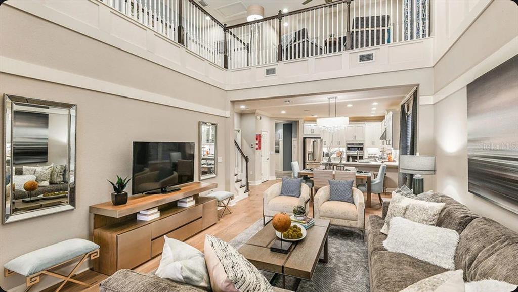 A two-story living room with a balcony overlooks an open-concept kitchen and dining area — 7004 FOXBORO WAY, NOKOMIS, FL