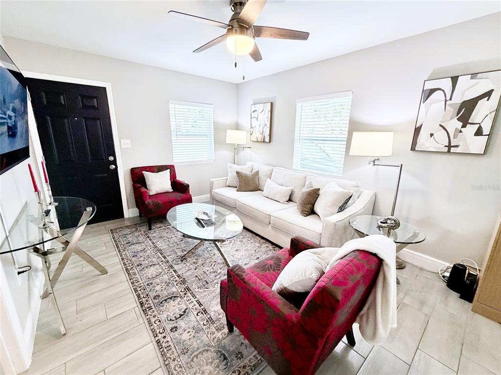A living room features a white sofa, two patterned red armchairs, and a glass coffee table — 1704 MARTIN L KING JR AVENUE, LAKELAND, FL
