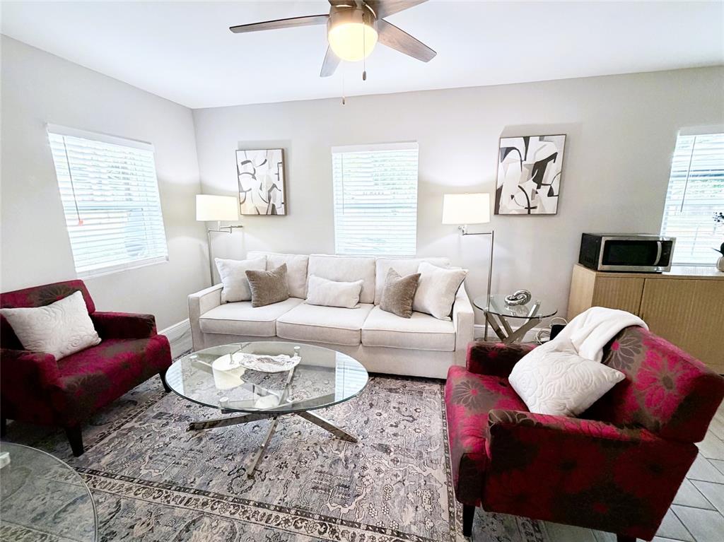 A living room features a white sofa, two patterned armchairs, and a glass coffee table — 1704 MARTIN L KING JR AVENUE, LAKELAND, FL