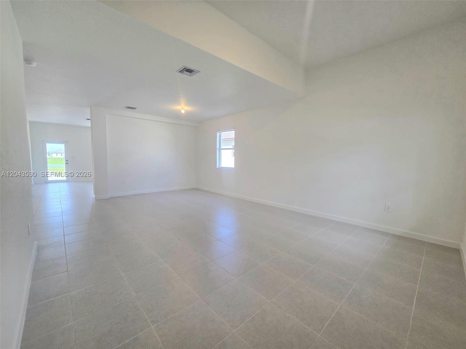 An empty room features white walls, light-colored tile flooring, and a single window — 2423 SE 30th St, Homestead FL 33035, HOMESTEAD, FL