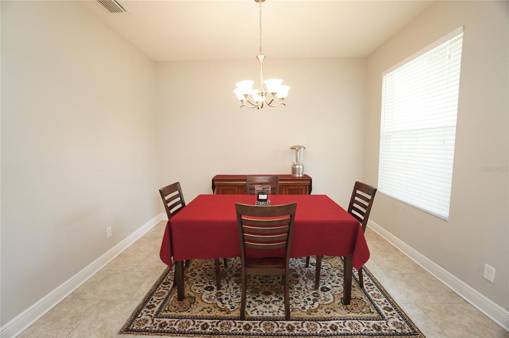 A dining room features a red-clothed table, wooden chairs, a rug, and a chandelier — 6303 S MACDILL AVENUE, TAMPA, FL