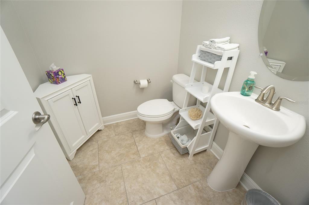 A small bathroom features a pedestal sink, a toilet, and a white corner storage cabinet — 6303 S MACDILL AVENUE, TAMPA, FL