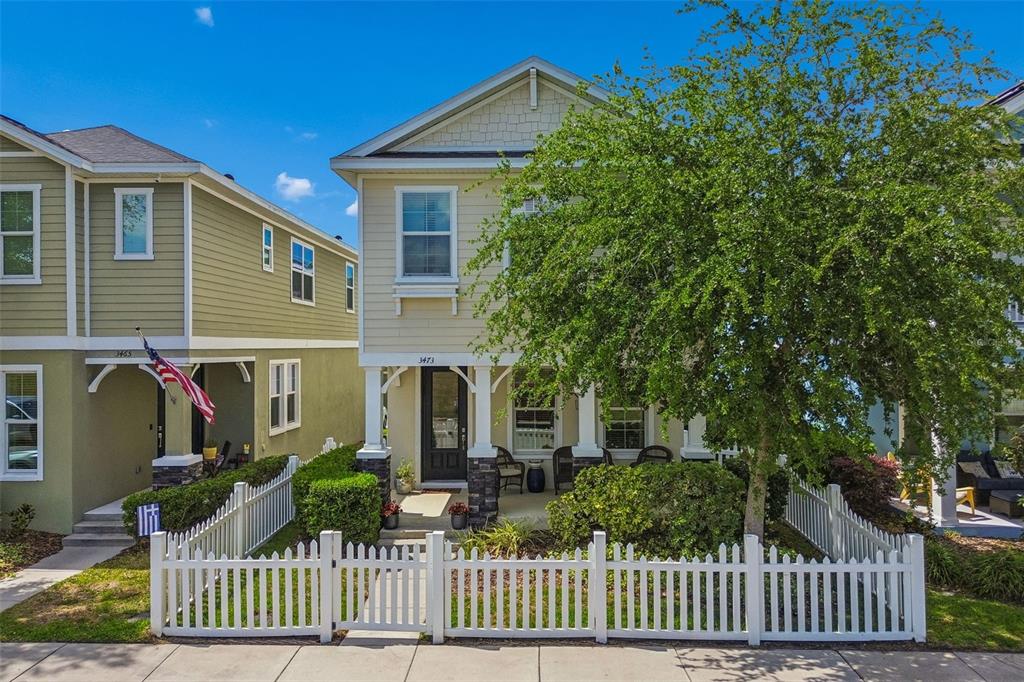 A two-story house with light siding, a front porch, and a white picket fence — 3473 BUMELIA LANE, NEW PORT RICHEY, FL