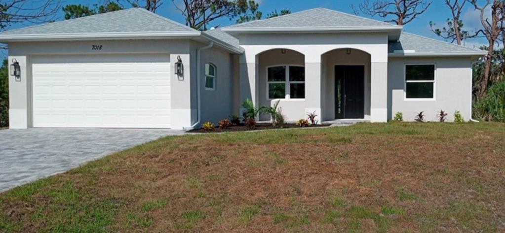 A single-story house with a two-car garage, arched entryway, and light-colored stucco exterior — 7197 TREADWAY ROAD, PORT CHARLOTTE, FL