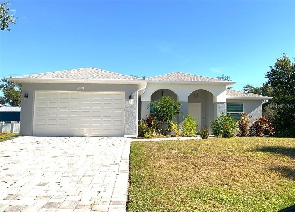 A single-story house with a gray stucco exterior, a paved driveway, and an arched entryway — 7197 TREADWAY ROAD, PORT CHARLOTTE, FL