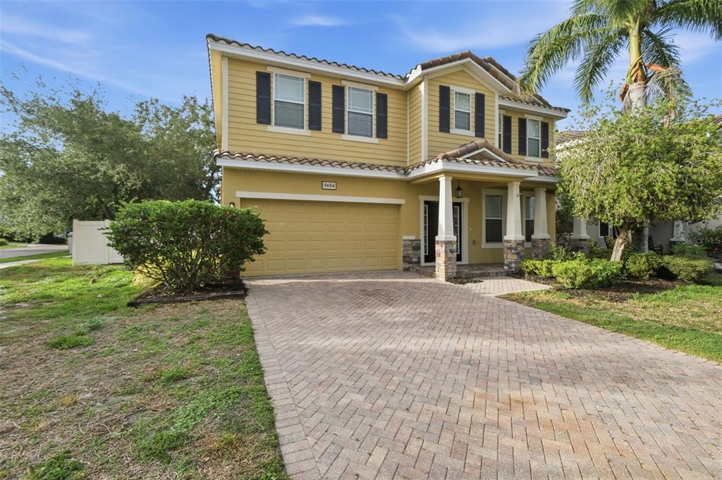 A two-story yellow house with a paved driveway, a two-car garage, and a palm tree — 5654 AARON COURT, SARASOTA, FL