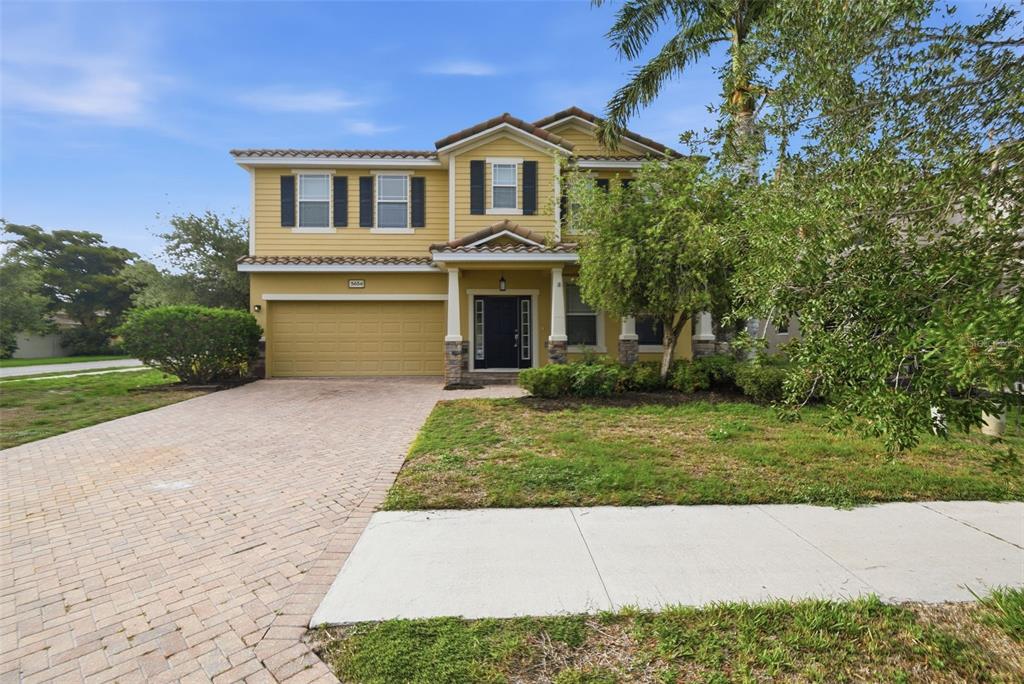 A two-story yellow house with a brick driveway, a garage, and a front porch — 5654 AARON COURT, SARASOTA, FL