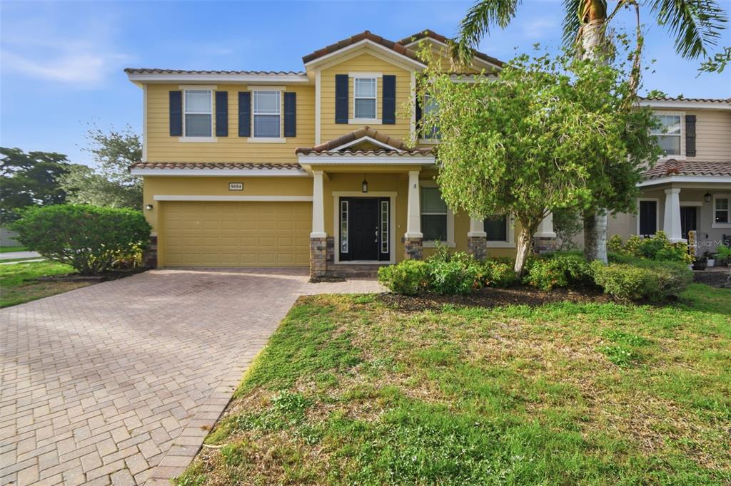 A two-story yellow house with a paved driveway, a two-car garage, and a front porch — 5654 AARON COURT, SARASOTA, FL