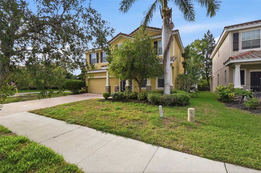 A two-story yellow house with a palm tree and a paved driveway in the front yard — 5654 AARON COURT, SARASOTA, FL