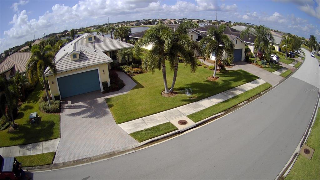 An aerial view shows a single-story house with a paved driveway and palm trees — 5117 TIDEWATER PRESERVE BOULEVARD, BRADENTON, FL