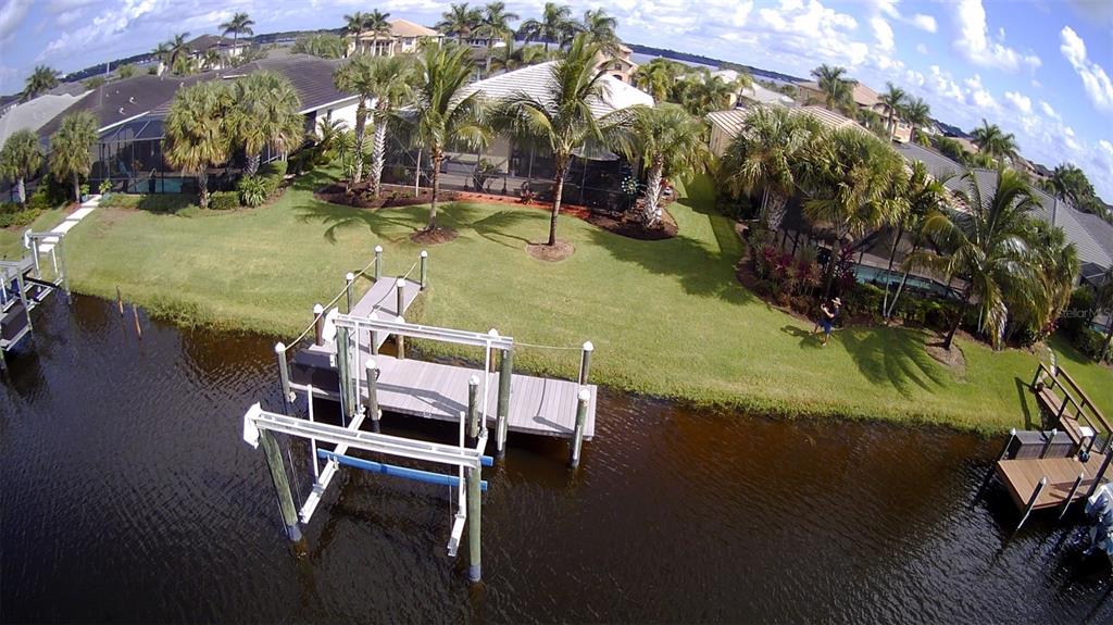 An aerial view shows a backyard lawn with a boat dock and lift on a canal — 5117 TIDEWATER PRESERVE BOULEVARD, BRADENTON, FL