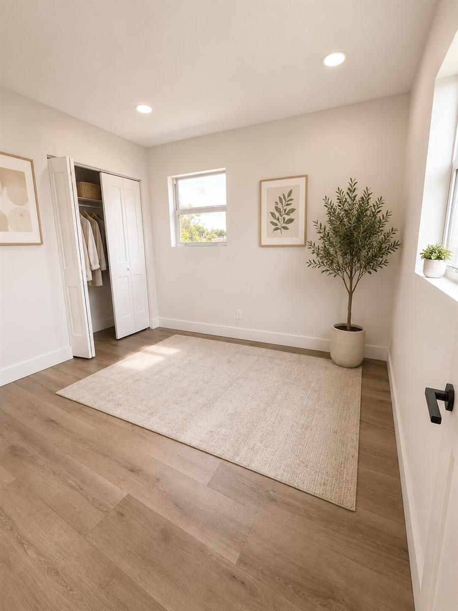 A bright bedroom features light wood-look flooring, a beige area rug, and a closet — 4181 Winchester Lane, FL 33406, FL