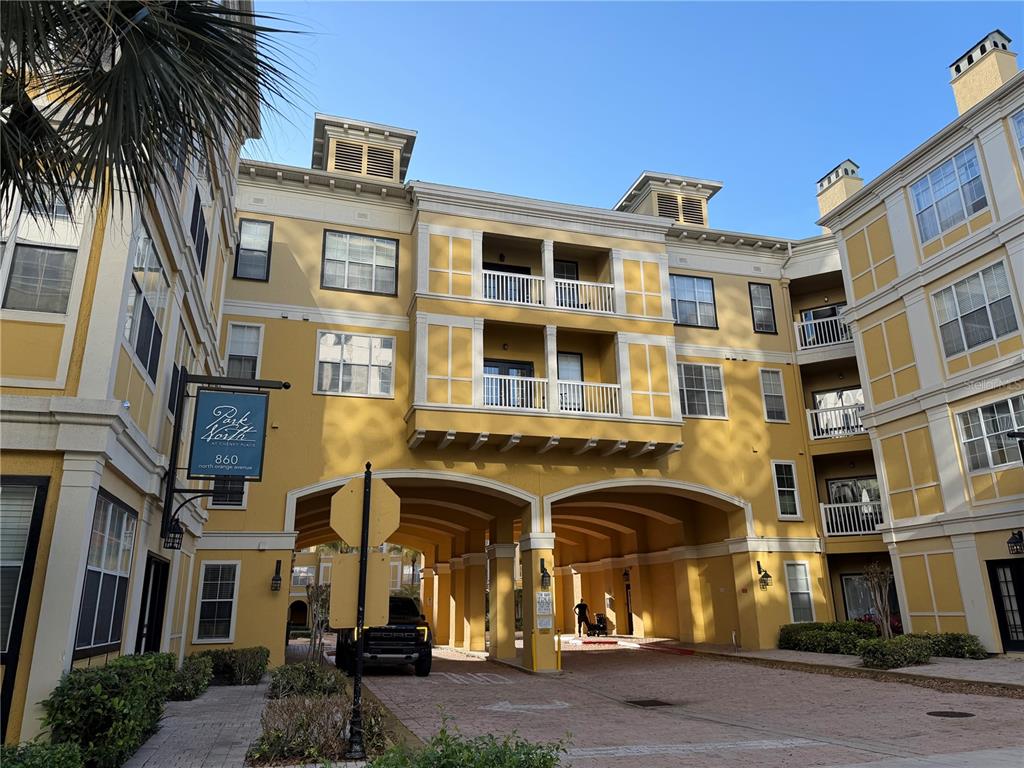 A multi-story yellow apartment building features a covered driveway entrance and balconies — 860 N ORANGE AVENUE UNIT 301, ORLANDO, FL