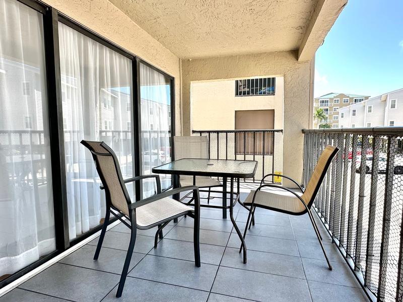 A balcony features a glass-top table with three chairs on a tiled floor — 19725 GULF BOULEVARD UNIT 43, INDIAN SHORES, FL