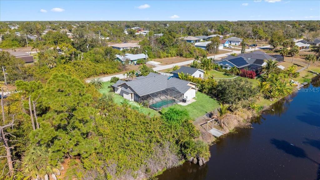 An aerial view of a house with a screened-in pool located next to a canal — 11195 SEABREEZE AVENUE, PORT CHARLOTTE, FL