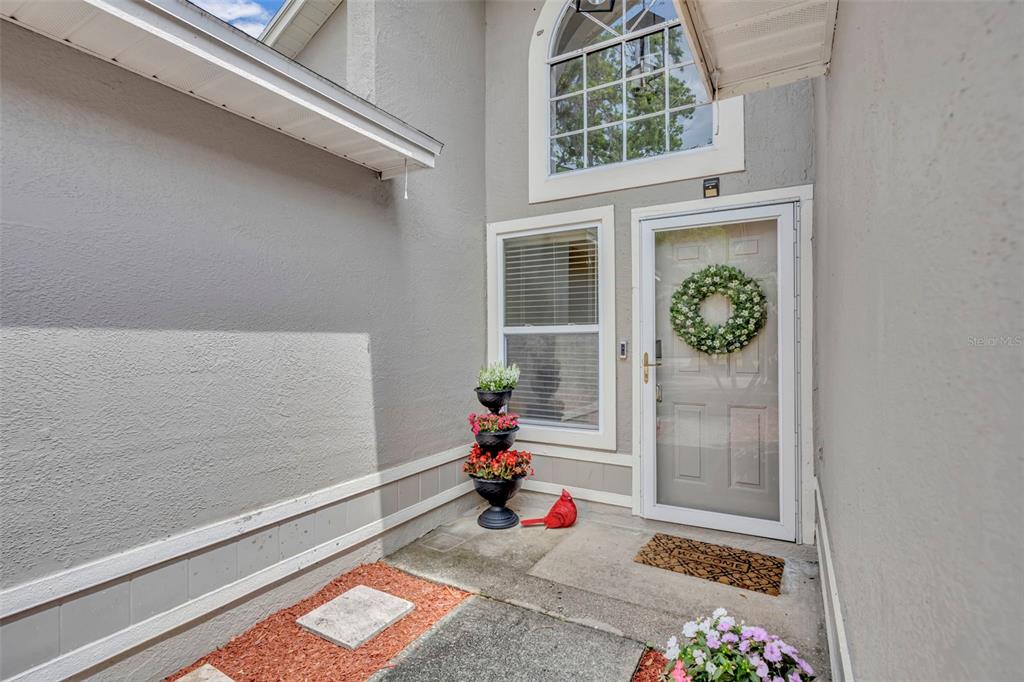 A front entryway features a gray door with a wreath, a window, and potted flowers — 1921 BLUE FOX COURT, ORLANDO, FL