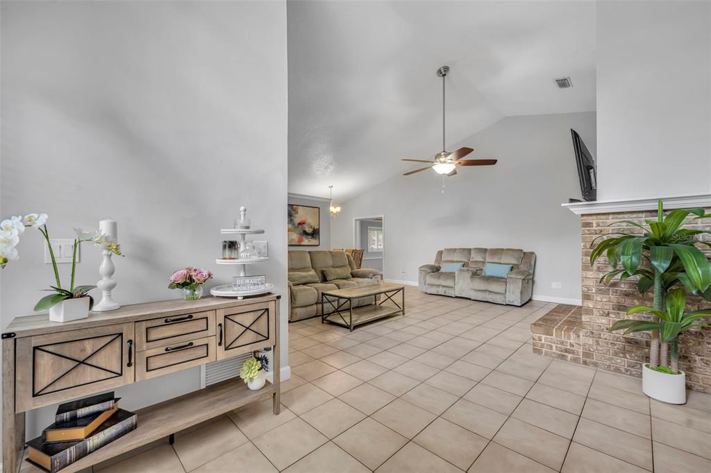 A living room features tile flooring, a brick fireplace, and a wooden console table — 1921 BLUE FOX COURT, ORLANDO, FL