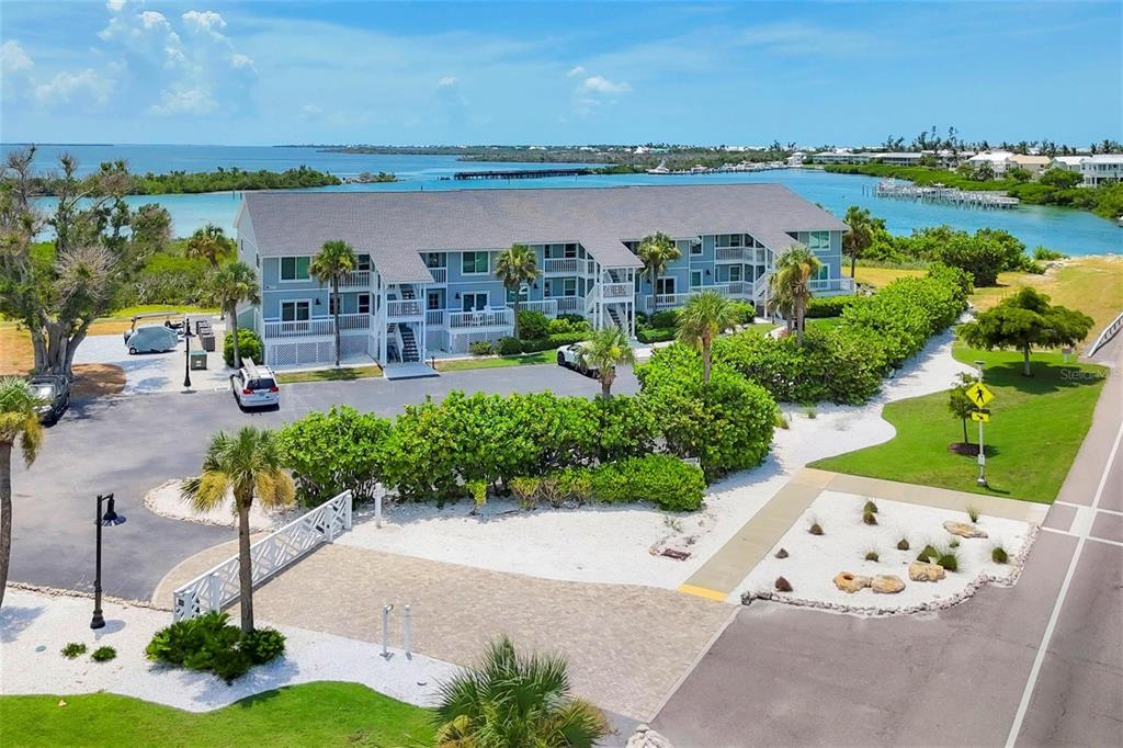 An aerial view of a multi-story blue apartment building surrounded by lush landscaping and water — 6000 BOCA GRANDE CAUSEWAY UNIT D38, BOCA GRANDE, FL