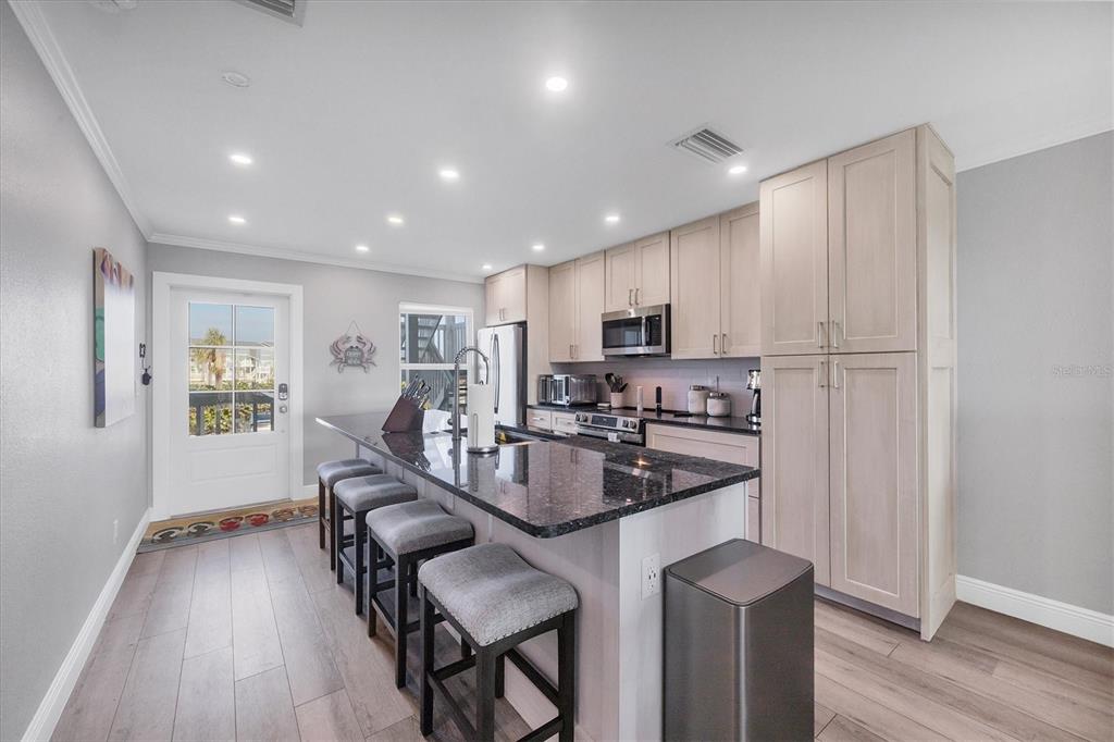 A kitchen features light wood cabinets, dark granite countertops, a breakfast bar, and stainless appliances — 6000 BOCA GRANDE CAUSEWAY UNIT D38, BOCA GRANDE, FL