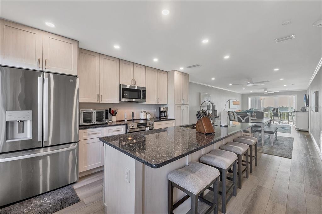 A modern kitchen features light wood cabinets, granite countertops, a large island, and stainless appliances — 6000 BOCA GRANDE CAUSEWAY UNIT D38, BOCA GRANDE, FL