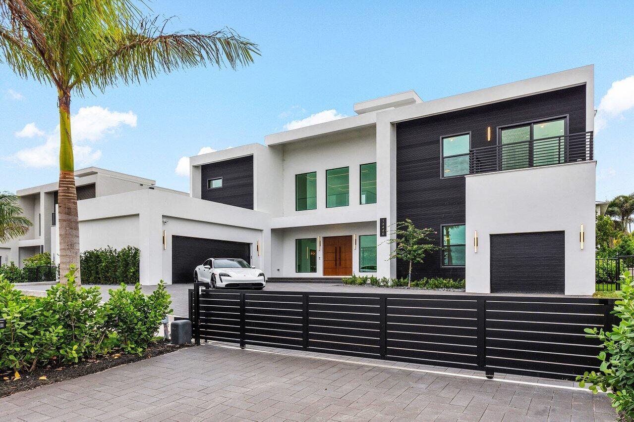 A modern two-story house with a black and white exterior, gated driveway, and palm tree — 13440 Us Highway 1, Juno Beach FL 33408, JUNO BEACH, FL