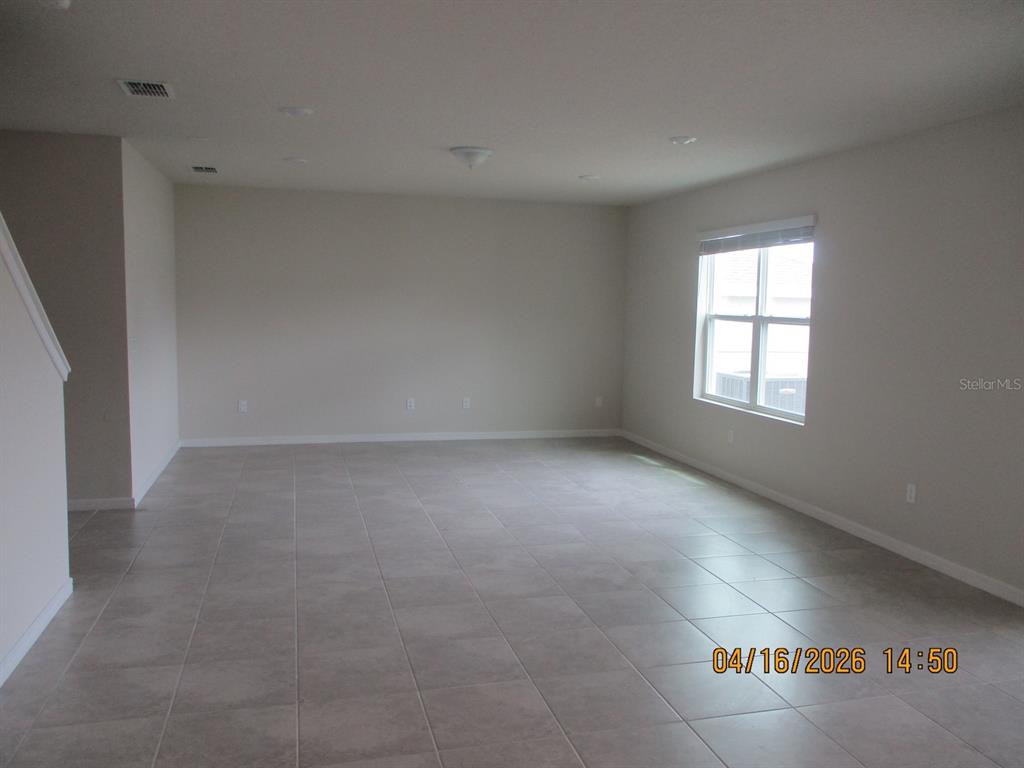 An empty room features light-colored tile flooring, neutral walls, recessed lighting, and a single window — 1608 ASPEN AVE, DAVENPORT, FL