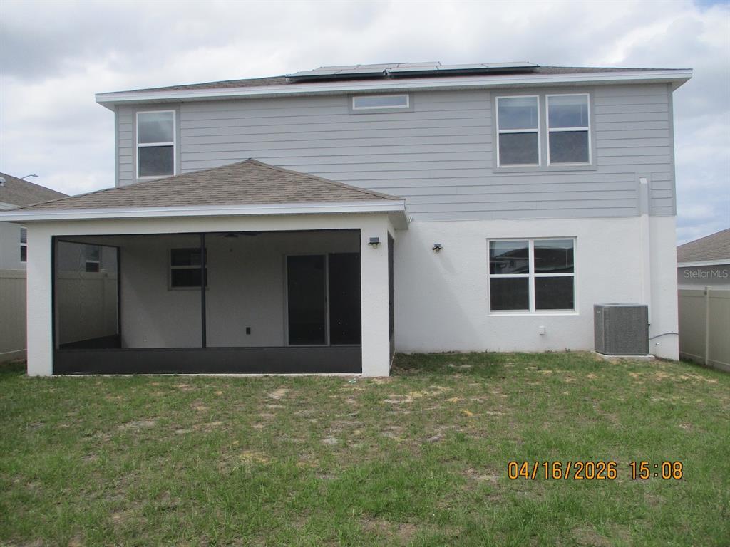 The rear exterior of a two-story house features a screened-in patio and solar panels — 1608 ASPEN AVE, DAVENPORT, FL