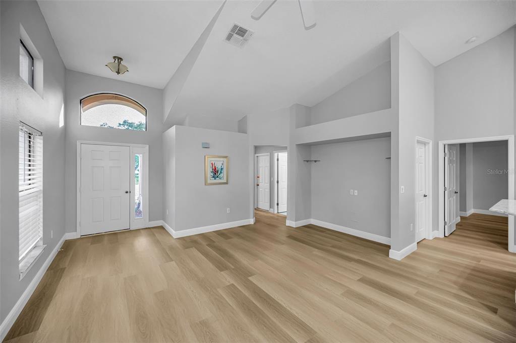 A bright living room with high vaulted ceilings, light wood flooring, and gray walls — 6240 FAIRSKIES DRIVE, NEW PORT RICHEY, FL