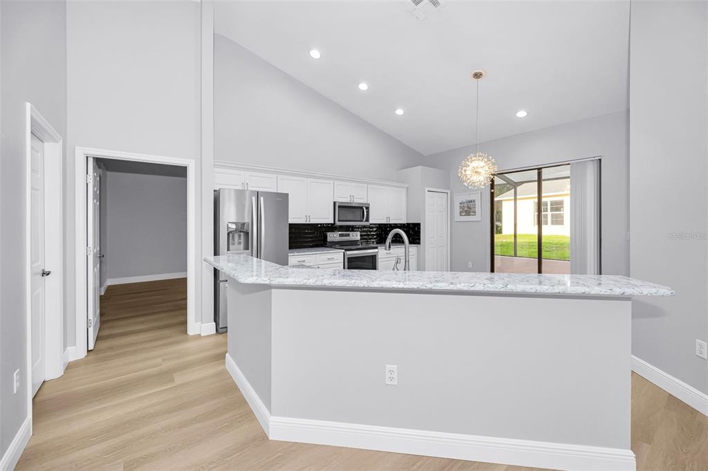 A kitchen with white cabinets, stainless steel appliances, and a granite-topped breakfast bar — 6240 FAIRSKIES DRIVE, NEW PORT RICHEY, FL