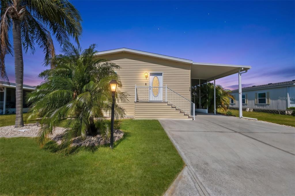 A single-story mobile home with tan siding, a front porch, and a concrete driveway — 530 SAN CLEMENTE CIRCLE, NORTH PORT, FL