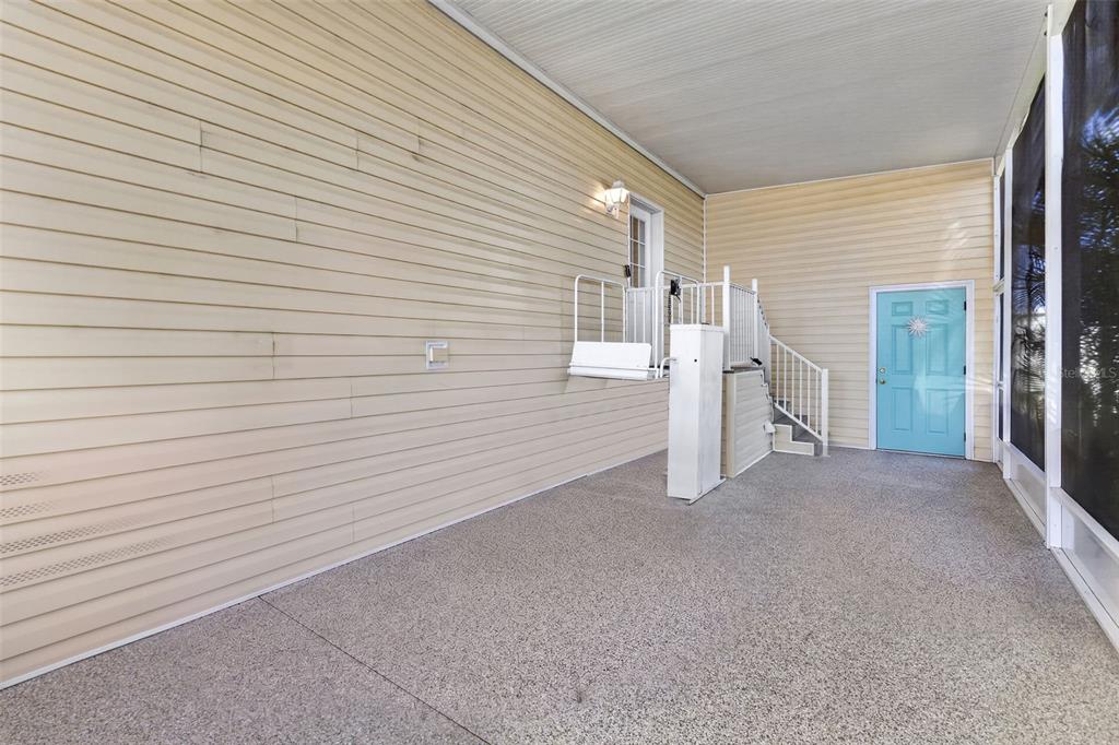 A covered patio features beige vinyl siding, a concrete floor, a staircase, and a wheelchair lift — 530 SAN CLEMENTE CIRCLE, NORTH PORT, FL
