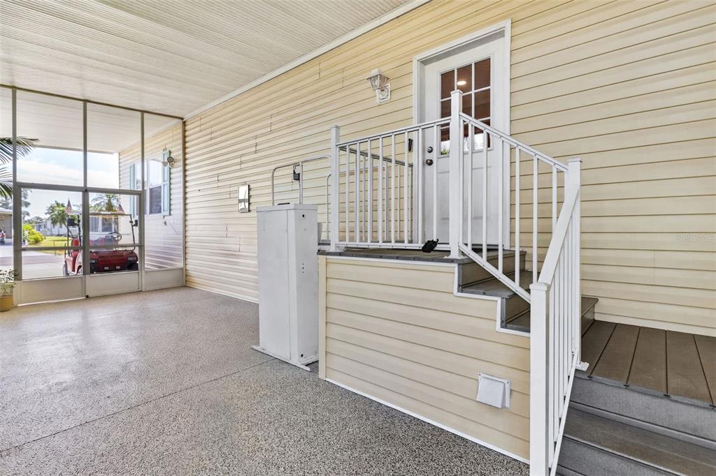 A covered patio features a wheelchair lift next to stairs leading to a white door — 530 SAN CLEMENTE CIRCLE, NORTH PORT, FL