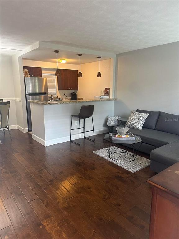 A living room with dark wood floors flows into a kitchen featuring a breakfast bar — 3718 W MCKAY AVENUE UNIT 101, TAMPA, FL