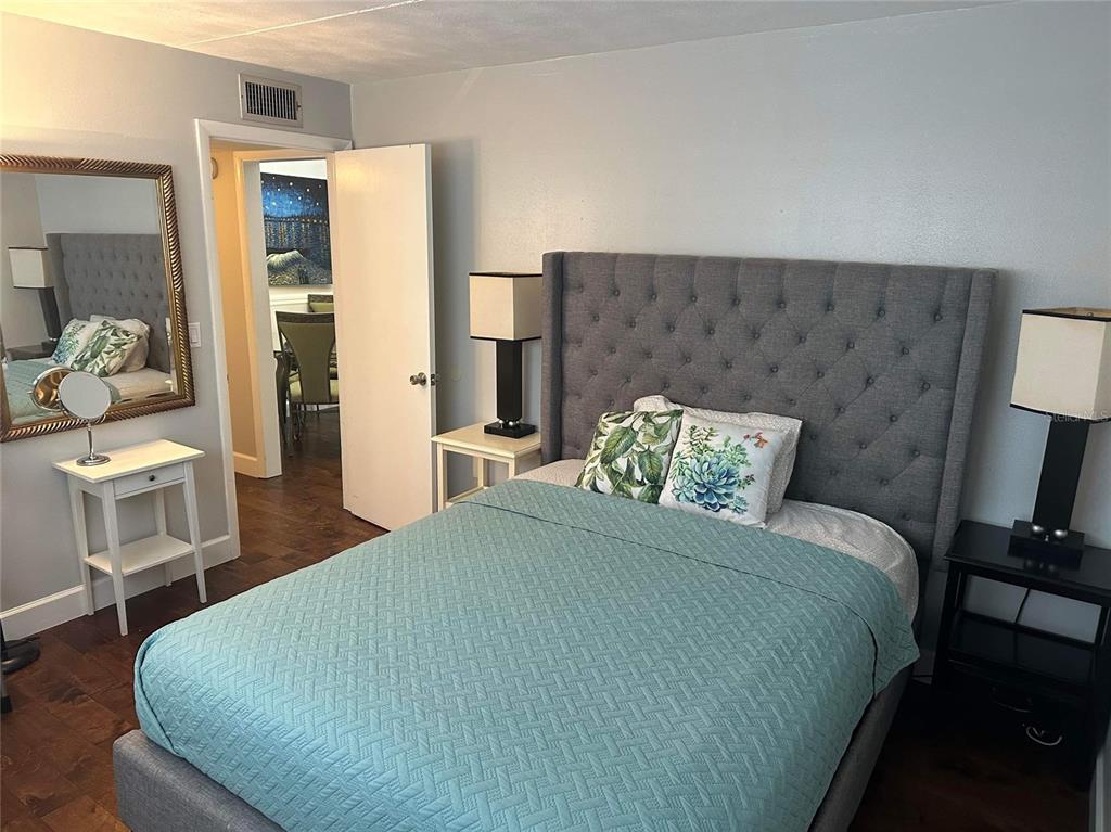 A bedroom features a gray tufted headboard, a teal quilt, and a doorway to another room — 3718 W MCKAY AVENUE UNIT 101, TAMPA, FL