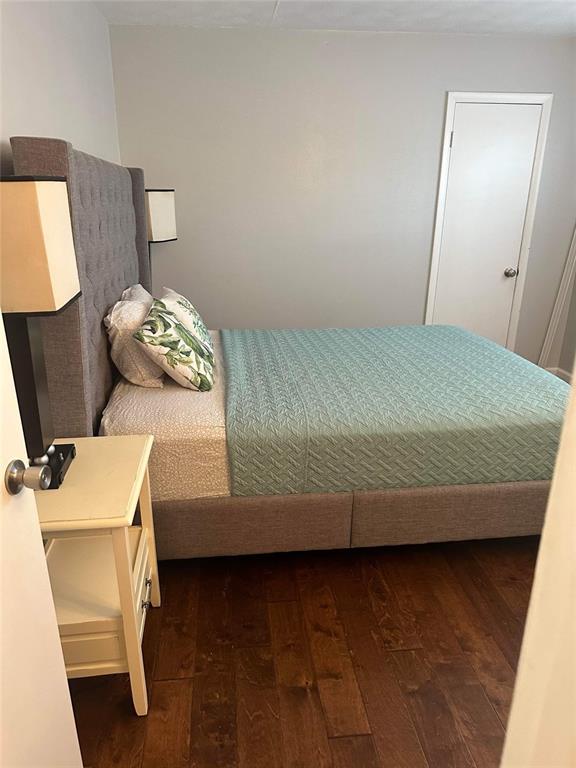 A bedroom features a gray upholstered bed, a white nightstand, and dark hardwood flooring — 3718 W MCKAY AVENUE UNIT 101, TAMPA, FL