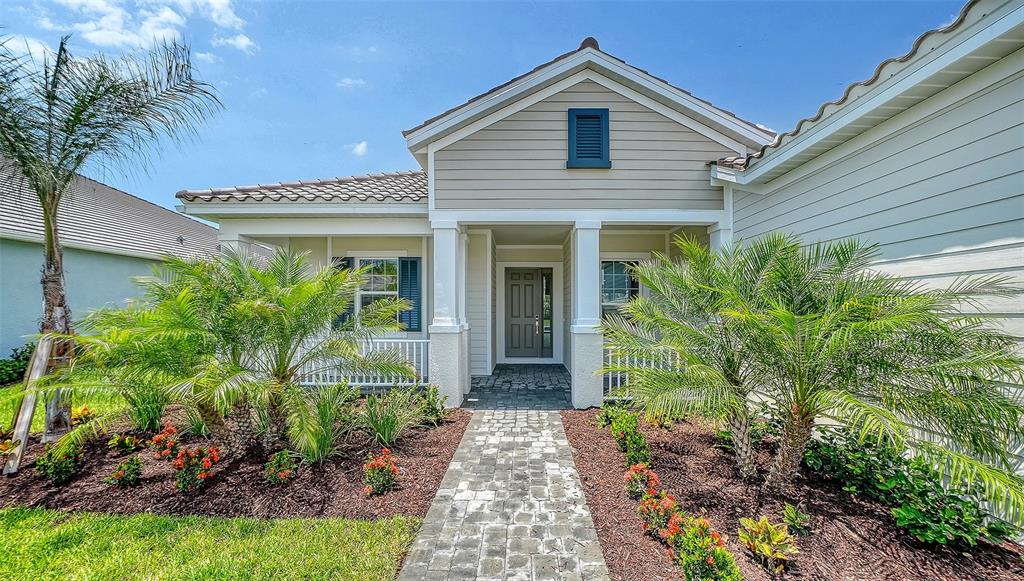 A single-story house exterior features a stone walkway, palm trees, and a covered front entrance — 6336 LAKE WOODRUFF COURT, SARASOTA, FL