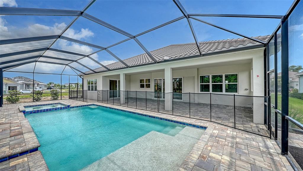 A screened-in patio features a swimming pool with a spa and paver decking — 6336 LAKE WOODRUFF COURT, SARASOTA, FL