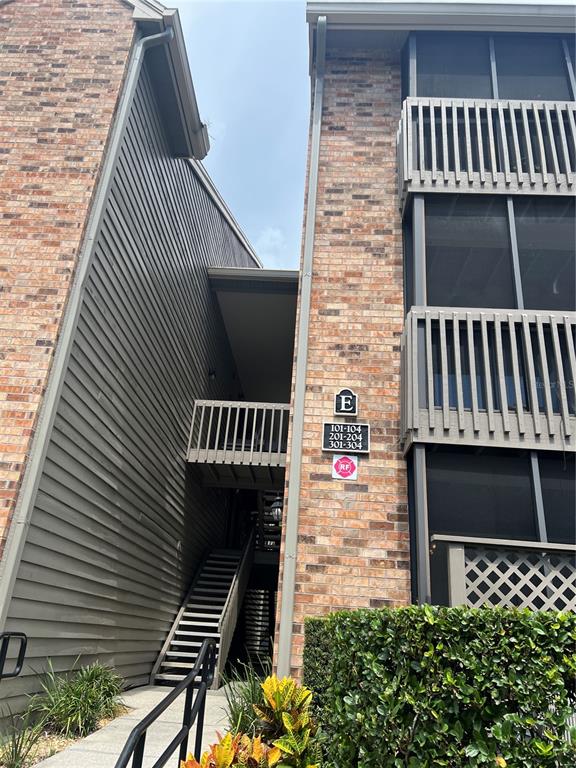 Exterior view of a brick and gray siding apartment building with an outdoor staircase — 2500 WINDING CREEK BOULEVARD UNIT E103, CLEARWATER, FL