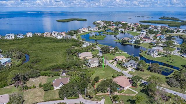 An aerial view shows a vacant residential lot situated between houses near a coastal waterway — 0 N POINTE ALEXIS DRIVE, TARPON SPRINGS, FL