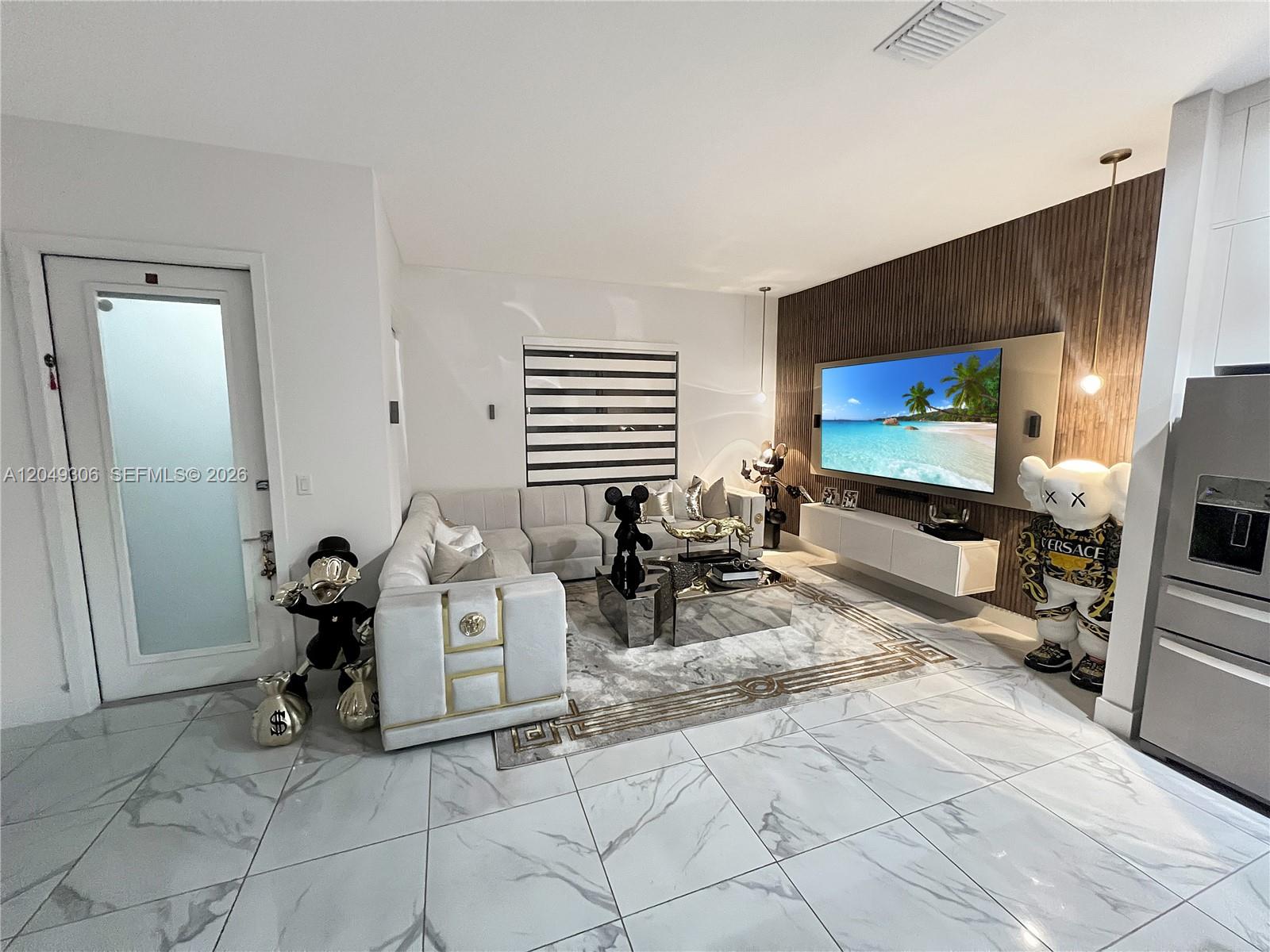 A modern living room features a white sectional sofa, marble flooring, and a wood-paneled wall — 4386 NW 80th Ct, Doral FL 33166, DORAL, FL