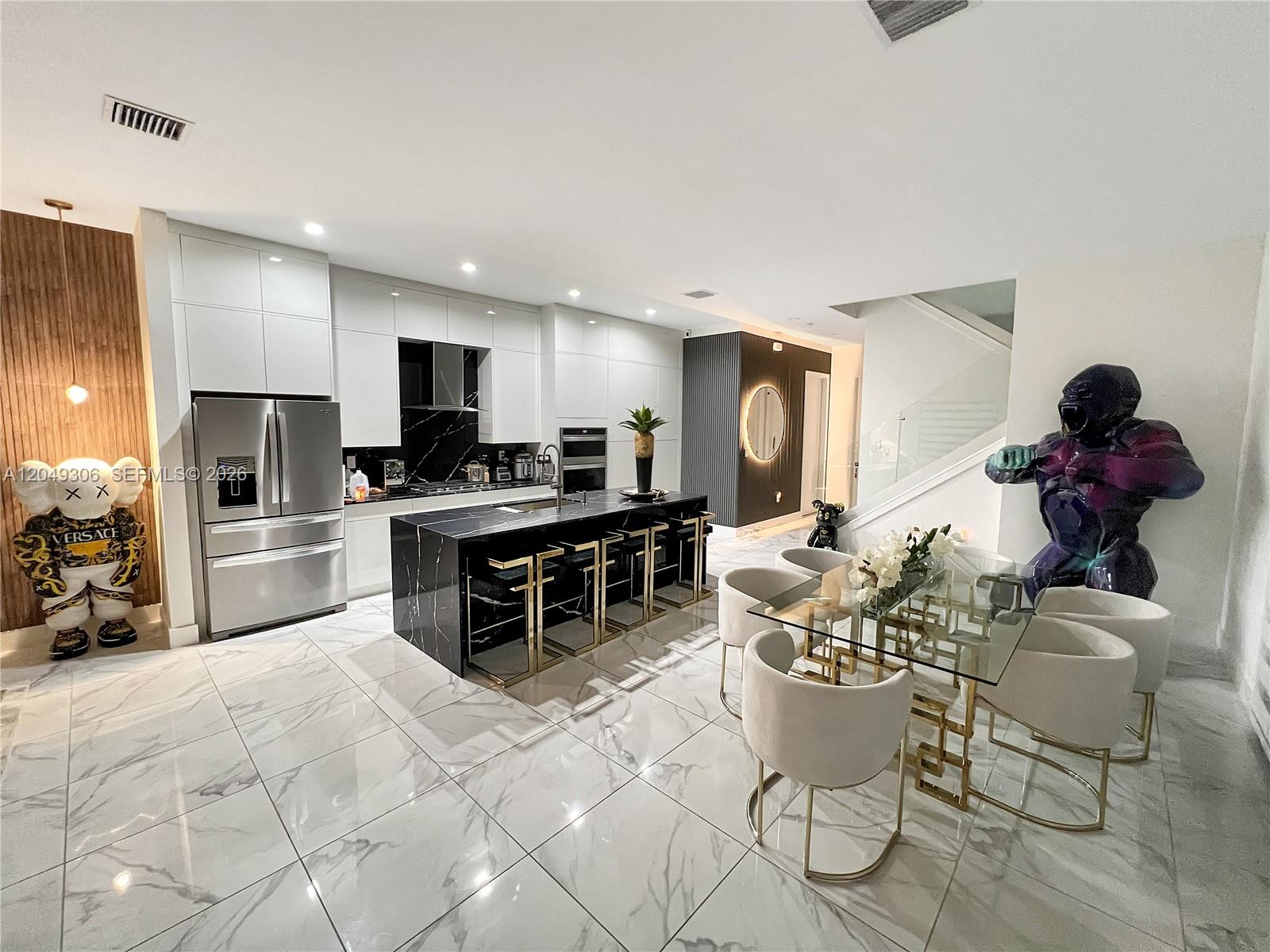 A modern kitchen and dining area feature marble floors, a black island, and designer sculptures — 4386 NW 80th Ct, Doral FL 33166, DORAL, FL