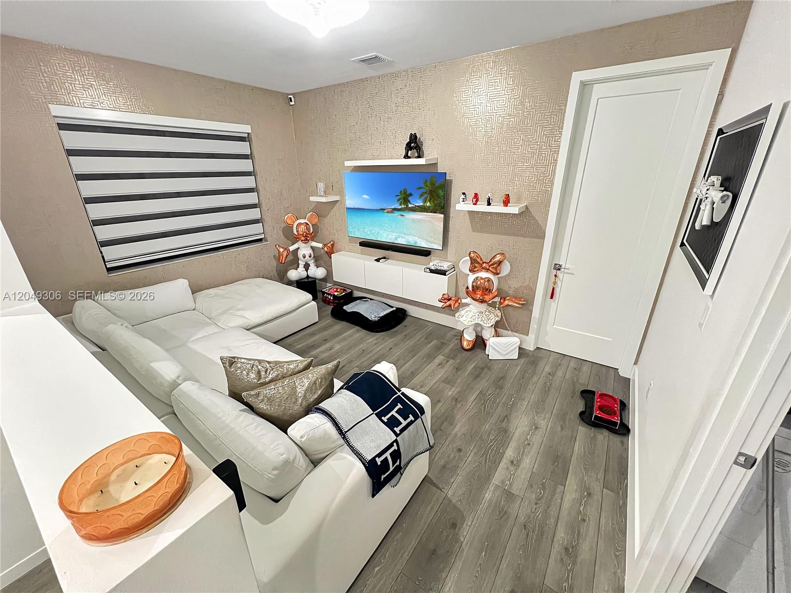 A living room features a white sectional sofa, a wall-mounted television, and patterned wallpaper — 4386 NW 80th Ct, Doral FL 33166, DORAL, FL