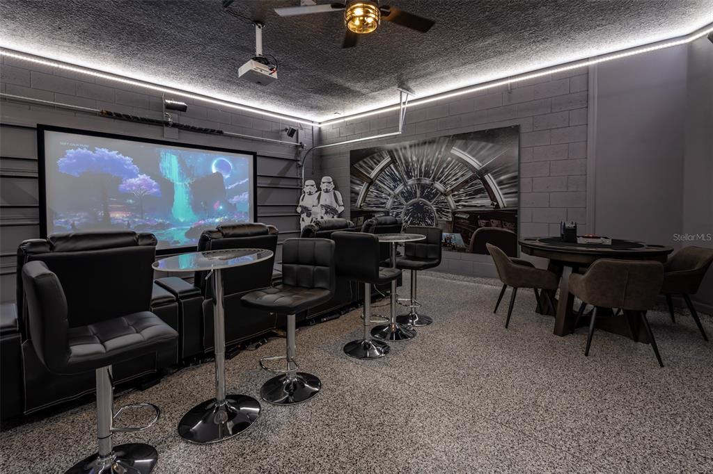A home theater room features a projector screen, tiered seating, and a round game table — 3811 LANA AVENUE, DAVENPORT, FL