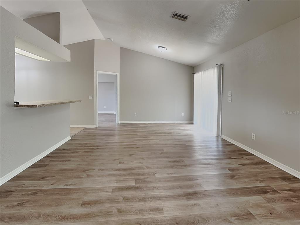 An open-concept living area features light gray walls, wood-look flooring, and a vaulted ceiling — 7352 BOLTEN LANE, PORT CHARLOTTE, FL