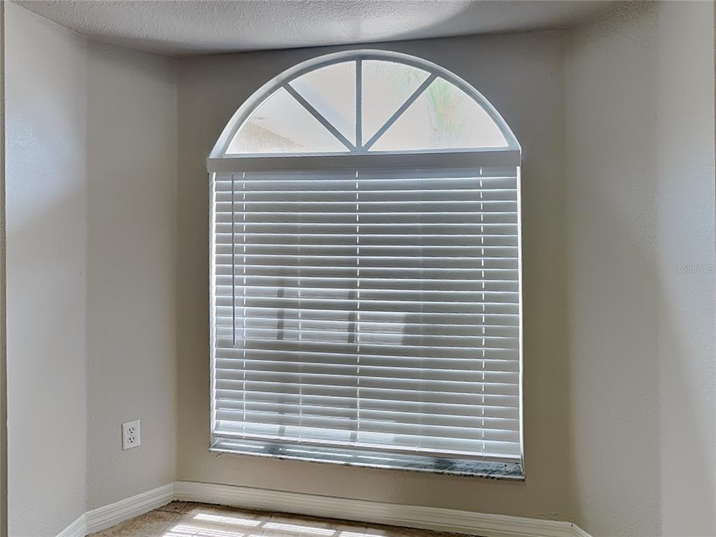 A window with white horizontal blinds and an arched top sits in a beige room — 7352 BOLTEN LANE, PORT CHARLOTTE, FL
