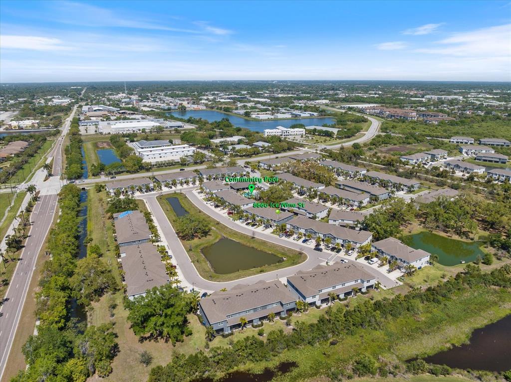An aerial view shows a residential townhouse community with a central pool and surrounding ponds — 8660 ICE WINE STREET, SARASOTA, FL