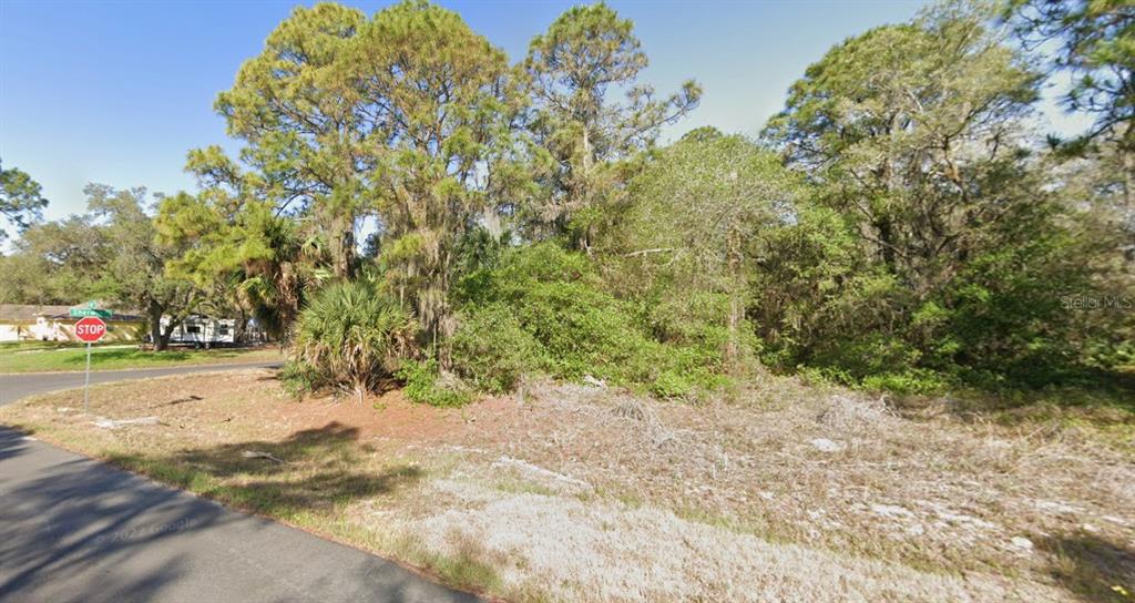 A vacant, wooded residential lot sits at a street corner near a stop sign — 1255 MILIKEN TERRACE, PORT CHARLOTTE, FL
