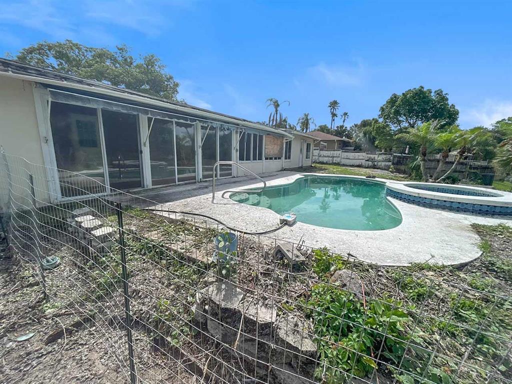 A backyard features a swimming pool, a spa, and a house with sliding glass doors — 1749 HAVERHILL DRIVE, DELTONA, FL
