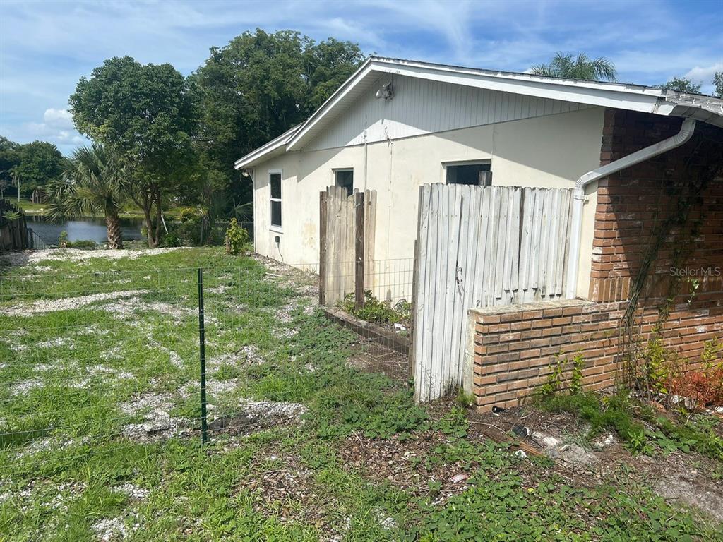 The exterior of a house features a brick corner, white siding, and a fenced yard — 1749 HAVERHILL DRIVE, DELTONA, FL